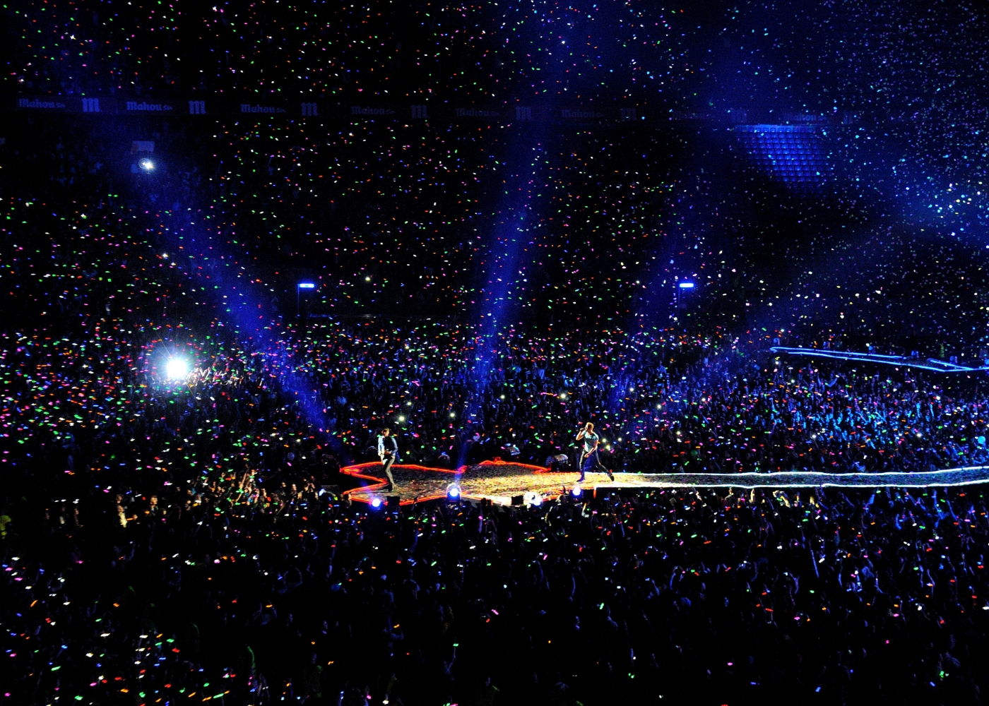 wide shot of aa Coldplay concert, the audience all have their phone lights on 